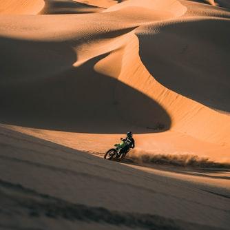 Ride a motor bike across a sand dune